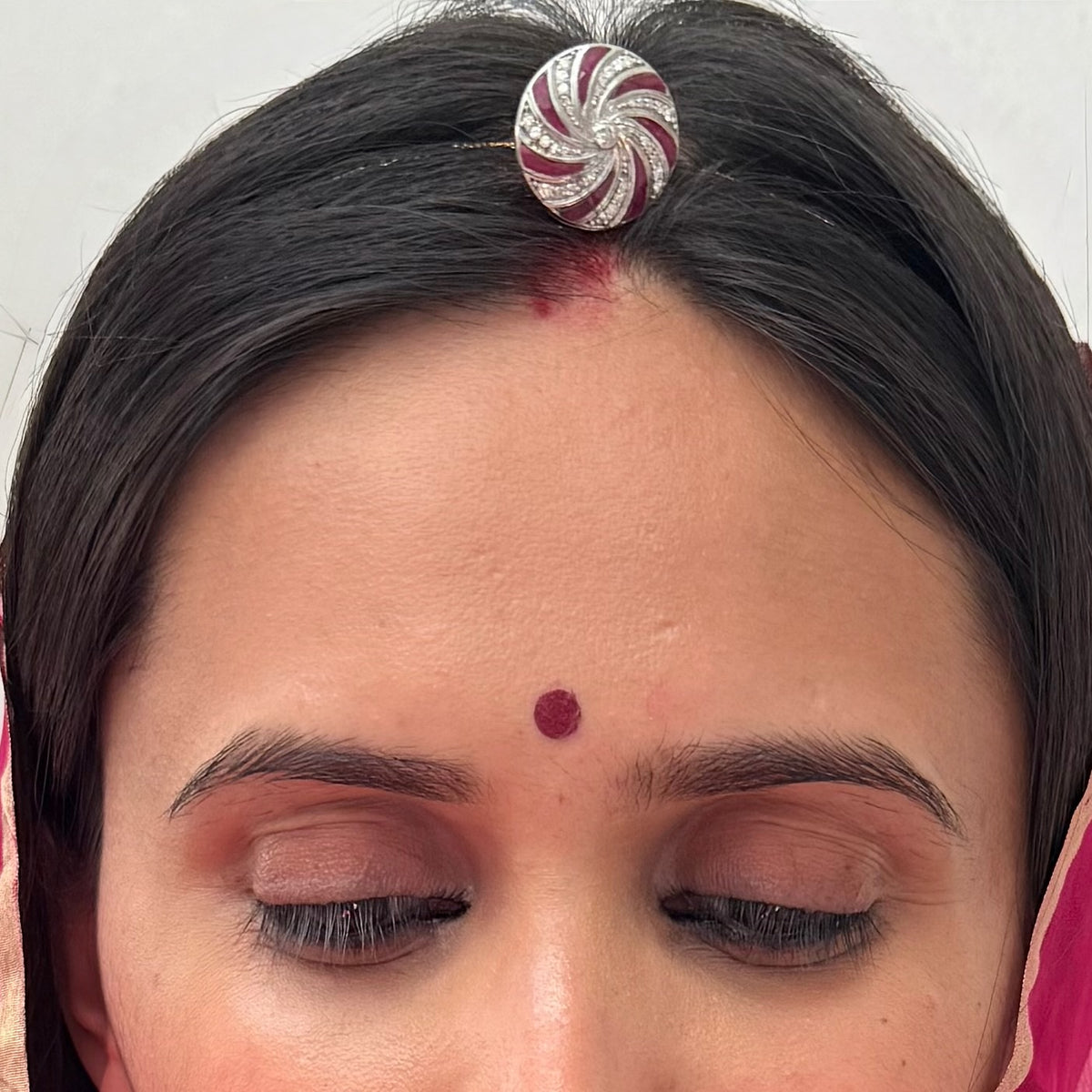 925 silver rakhdi with a geometric ruby and CZ pinwheel design, platinum finish