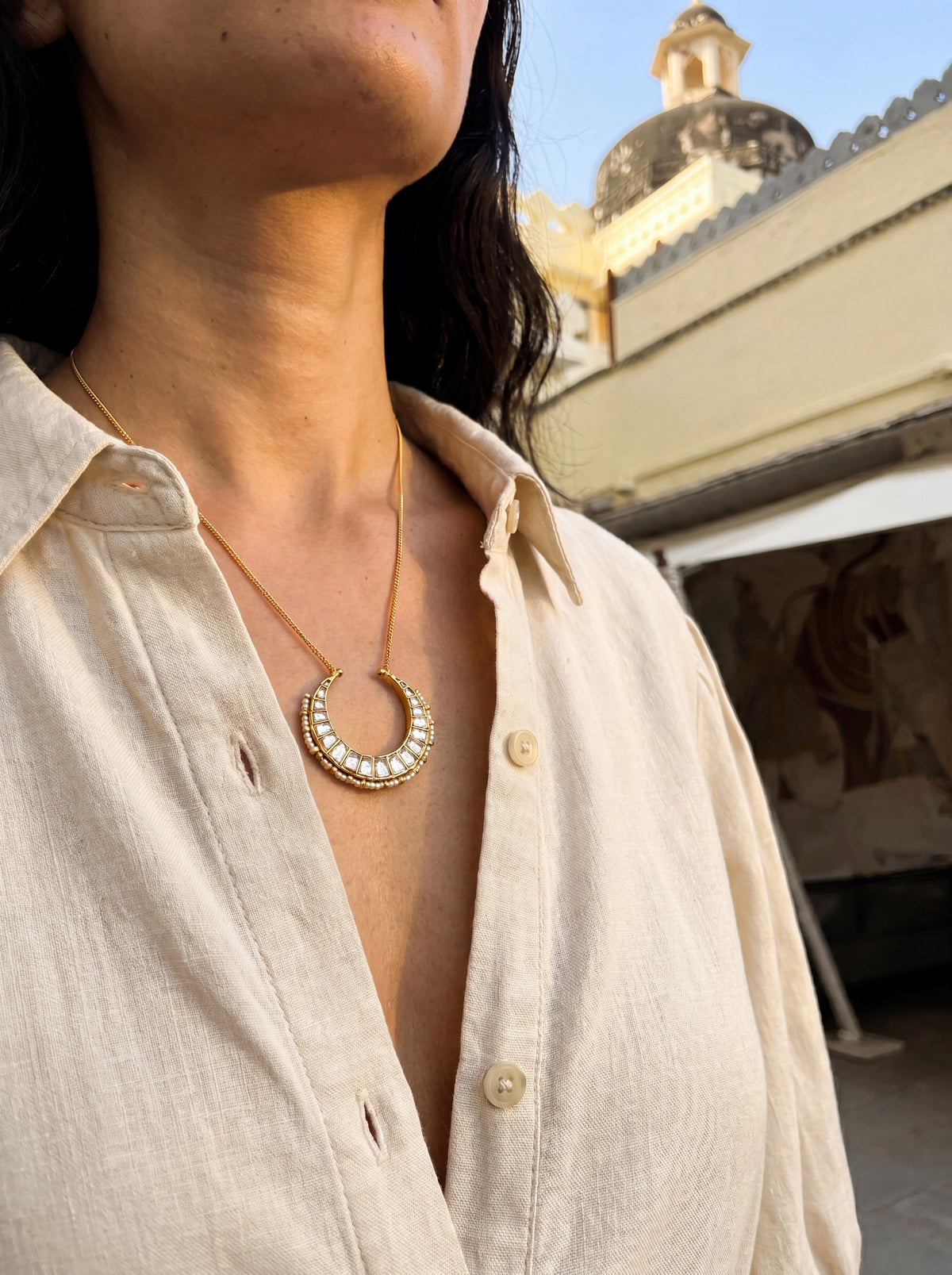 Kundan Polki crescent pendant with a seed-pearl border on a gold curb chain