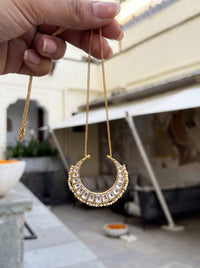 Kundan Polki crescent pendant with a seed-pearl border on a gold curb chain