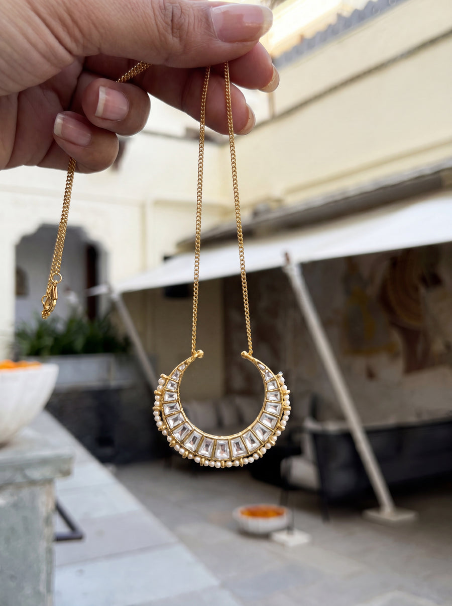 Kundan Polki crescent pendant with a seed-pearl border on a gold curb chain