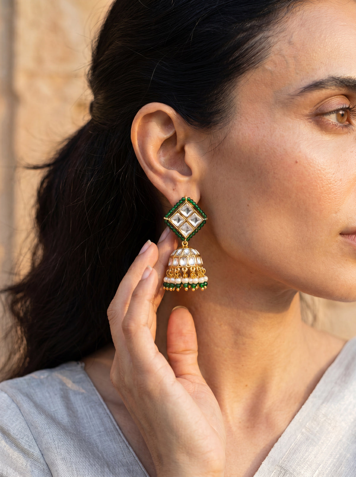 Kundan jhumka earrings with an emerald bead border and pearl-green fringe