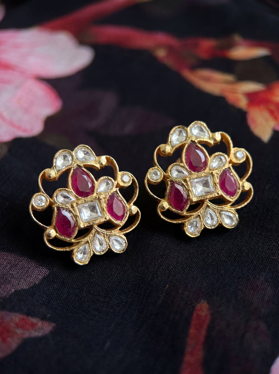 Kundan stud earrings with an open filigree scroll and deep ruby cluster