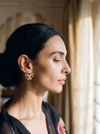 Kundan stud earrings with an open filigree scroll and deep ruby cluster