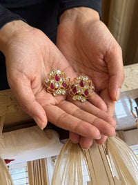 Kundan stud earrings with an open filigree scroll and deep ruby cluster